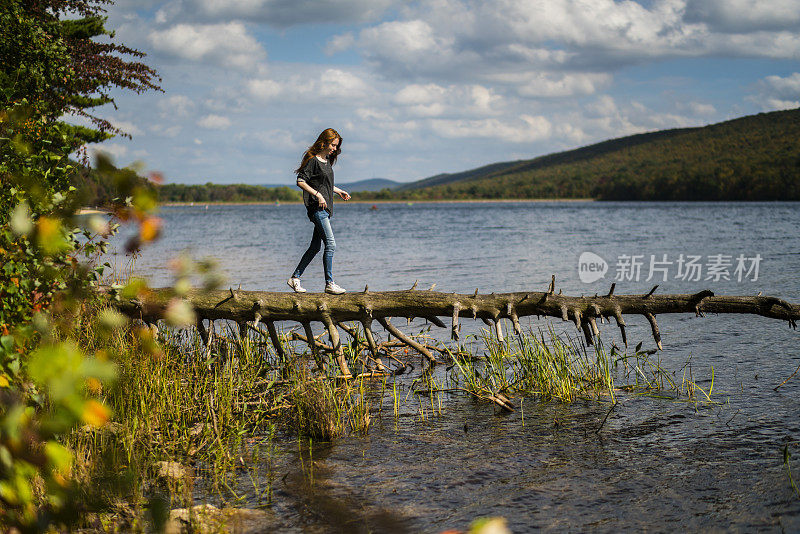 在波科诺斯的Mauch Chunk湖上，一名少女走在倒下的树上